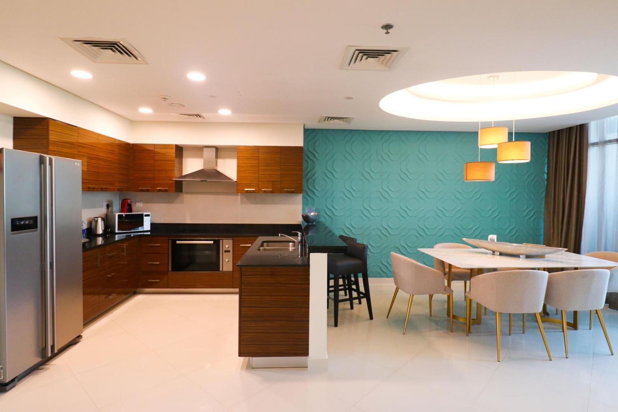 Lagoona Beach Luxury Resort And Spa Manama Exterior foto The photo shows a modern kitchen and dining area. The kitchen features wooden cabinets, sleek appliances including a stainless steel refrigerator, microwave, and an oven. There is a dark countertop and a small breakfast bar with high stools. The wall